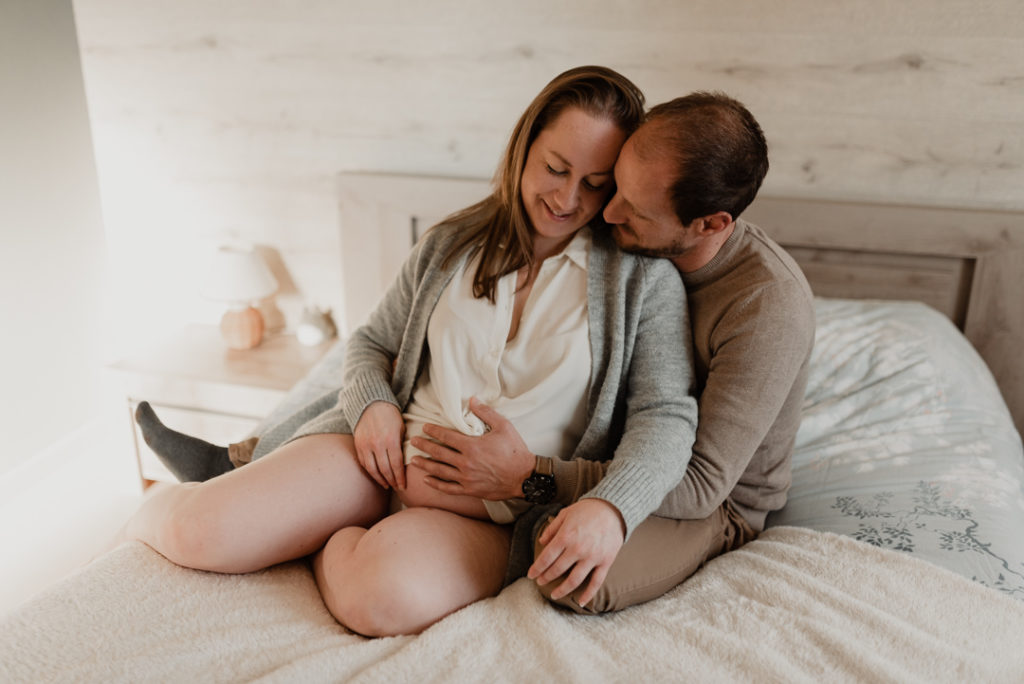 Futurs parents enlacés sur un lit