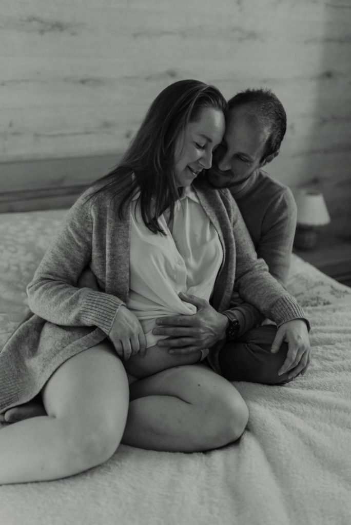 Futurs parents enlacés sur un lit - noir et blanc