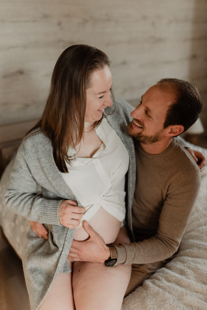 Femme enceinte assise sur les genoux de son compagnon