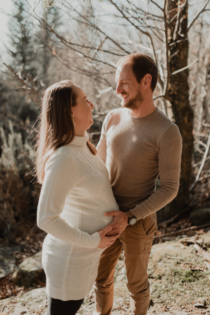 Futurs parents rigolant en forêt