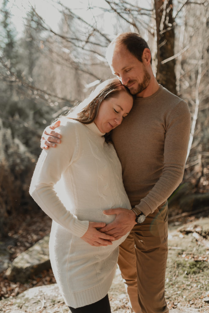 Futurs parents se câlinant en forêt.