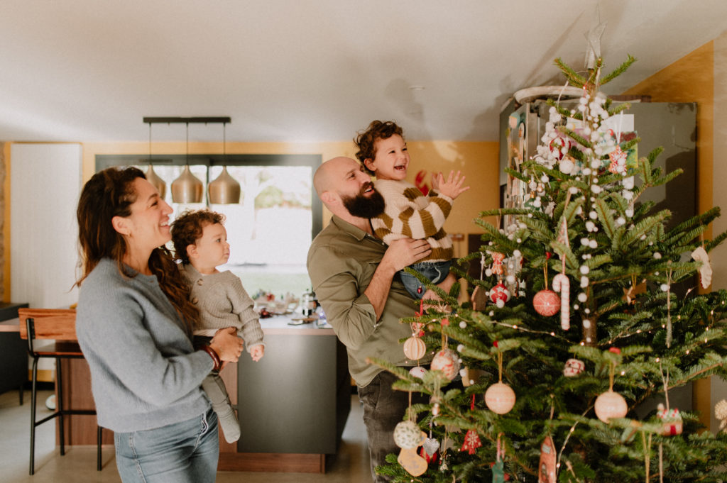 Une famille décore le sapin de Noël en mettant l'étoile au sommet